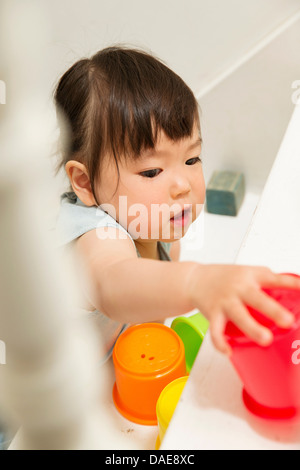 Weiblichen Kleinkind spielen mit Spielzeug auf Treppe Stockfoto