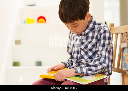 Kleiner Junge sitzend auf Stuhl studierte Spiel Stockfoto