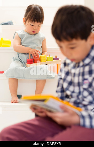 Bruder und Schwester spielt mit Spielzeug auf Treppe Stockfoto