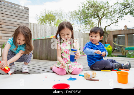 Drei kleine Kinder malen und zeichnen im Garten Stockfoto