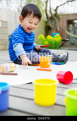 Männliche Kleinkind Zeichnung im Garten Stockfoto