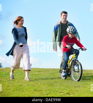 Eltern beobachten Sohn Reiten Fahrrad Stockfoto