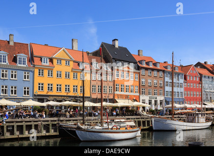 Hölzerne Boote vertäut am Kanal mit Cafés und farbenfrohen Gebäuden am Wasser im Hafen von Nyhavn Kopenhagen Seeland Dänemark Stockfoto