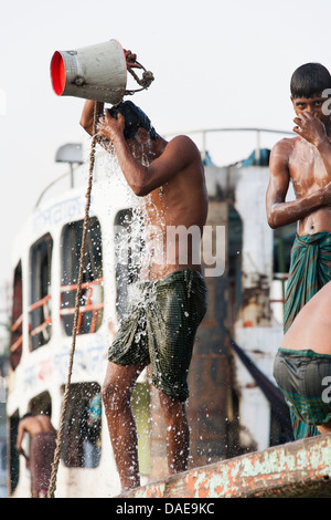 Eine Besatzung von einem Fluss Fähre oder Start waschen mit Eimern und Flusswasser bei Sadarghat am Fluss Buriganga in Dhaka, Bangladesch. Stockfoto