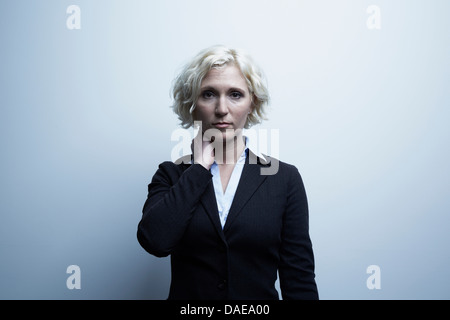 Studio-Porträt der Geschäftsfrau mit Hand am Hals Stockfoto