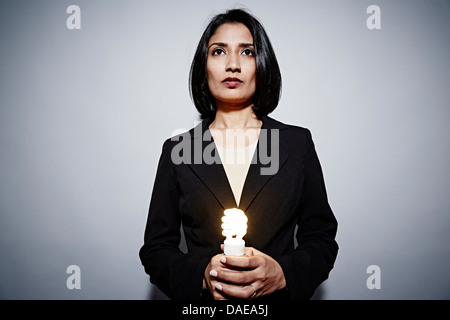 Studio-Porträt der Geschäftsfrau hält energiesparende Glühbirne Stockfoto