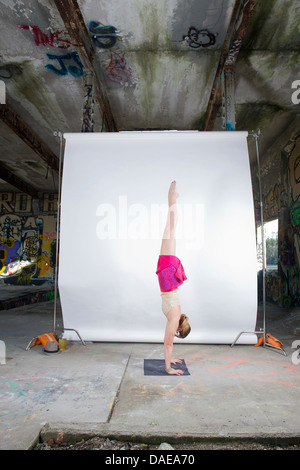 Weibliche Acrobat üben Handstand in alten industriellen Interieur Stockfoto