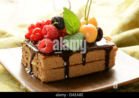 Schokoladenkuchen mit Beeren (Himbeere, Johannisbeere, Kirsche) und Schokoladensauce Stockfoto