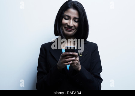 Studio-Porträt der Geschäftsfrau Blick auf Handy Stockfoto