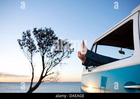 Füße aus Camper van Fenster in der Abenddämmerung Stockfoto