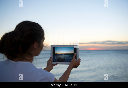 Junge Frau mit ihrer digital-Tablette bei Sonnenuntergang fotografieren Stockfoto