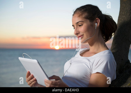 Nahaufnahme der jungen Frau, die digital-Tablette bei Sonnenuntergang betrachten Stockfoto