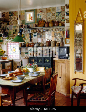 Alte Kiefern Tisch und Stühle im unübersichtlichen Cottage-Küche mit schmalen Spiegel an der Wand Stockfoto