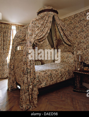 Schlafzimmereinrichtungen Bett mit Toile-de-Jouy drapiert und in französischer Landhaus Schlafzimmer mit co-Ordinating Tapeten und Stoff quilt Stockfoto