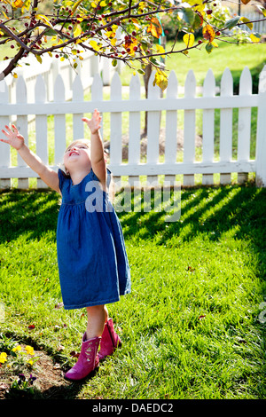 Junges Mädchen in Jeanskleid und rosa Cowboystiefel bis Baum Stockfoto