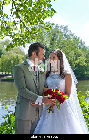Attraktive glückliche Braut und Bräutigam married just, posiert in riverside Kirche Gründen Stockfoto