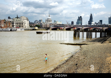 Busker stehend in der Themse an der South Bank mit der Londoner City im Hintergrund, England Großbritannien Stockfoto