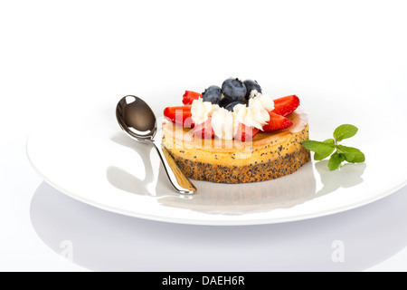 Käsekuchen mit Erdbeeren, Heidelbeeren, Minze und Sahne auf weißen Teller. Stockfoto