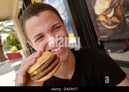 Ein 18-j hrige Mann isst Fast Food. Stockfoto