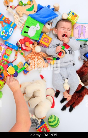 weinende Baby lag zwischen Spielzeug Stockfoto