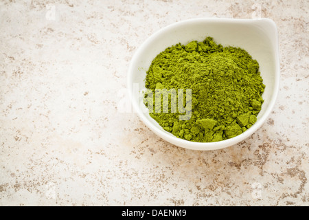 Moringa Blattpulver in einer kleinen Schüssel gegen eine keramische Fliese Hintergrund Stockfoto