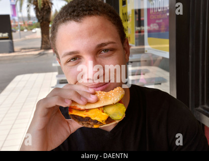 Ein 18-j hrige Mann isst Fast Food. Stockfoto