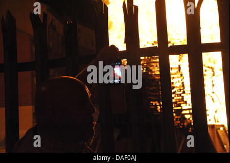 Belfast, Nordirland. 11. Juli 2013. Am 11. Juli werden standhaft protestantischen Gebieten "Elfte Nacht" Freudenfeuer angezündet. Viele sind massive Konstruktionen aus Holz Paletten, alte Sofas und Gummireifen, garniert mit irischen Fahnen oder Bildnisse von pro-Nationalist zahlen. Lagerfeuer Architekten Schlacht es sehen, wer der größte aufbauen kann und Verschiebungen der junge Wächter sicherzustellen, dass die rivalisierende Bauherren nicht brennbarer Beute stehlen. Um Mitternacht die Freudenfeuer angezündet werden, und diese wütenden Infernos lodernden quer durch die Stadt zu sehen. Im Bild: Sandy Row Lagerfeuer. Bildnachweis: Andrew Chittock/Alamy Live-Nachrichten Stockfoto