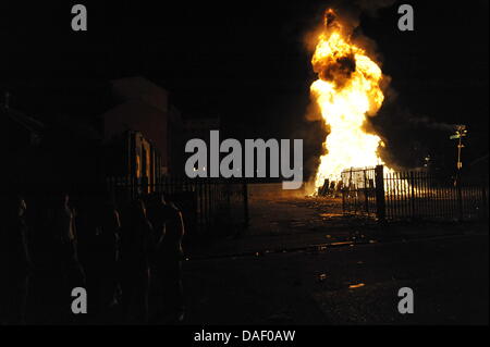 Belfast, Nordirland. 11. Juli 2013. Am 11. Juli werden standhaft protestantischen Gebieten "Elfte Nacht" Freudenfeuer angezündet. Viele sind massive Konstruktionen aus Holz Paletten, alte Sofas und Gummireifen, garniert mit irischen Fahnen oder Bildnisse von pro-Nationalist zahlen. Lagerfeuer Architekten Schlacht es sehen, wer der größte aufbauen kann und Verschiebungen der junge Wächter sicherzustellen, dass die rivalisierende Bauherren nicht brennbarer Beute stehlen. Um Mitternacht die Freudenfeuer angezündet werden, und diese wütenden Infernos lodernden quer durch die Stadt zu sehen. Im Bild: Sandy Row Lagerfeuer. Bildnachweis: Andrew Chittock/Alamy Live-Nachrichten Stockfoto