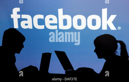 Datei - ILLUSTRATION - eine Archiv Bild 26. April 2010 datiert zeigt die Schatten von zwei Personen mit ihren Laptops vor dem Facebook-Logo in Straubing, Deutschland. Medienberichten zufolge plant Facebook seinen Börsengang im Jahr 2012. Foto: Armin Weigel Stockfoto