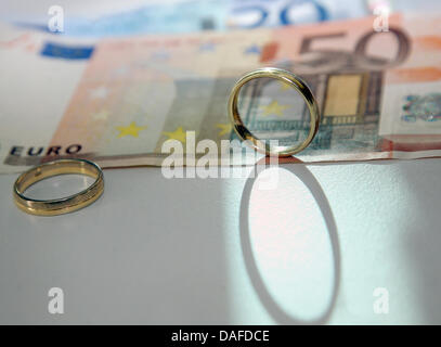 Zwei Trauringe und Euro-Banknoten liegen auf einem Tisch in Berlin, Deutschland, 11. Februar 2011. Das deutsche Verfassungsgericht der Bundesrepublik hat es für geschiedene Ehegatten auf Nachfrage Unterhaltszahlungen erleichtert. Foto: Stephanie Pilick Stockfoto