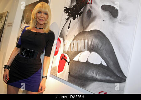 Ehemaliger Pornostar Nora Dvorak aka Dolly Buster lächelt neben ihr Gemälde "Shooting" (R) während der Vernissage ihrer Ausstellung in Fürth, Deutschland, 24. Februar 2011. Insgesamt 31 Bilder von Dolly Buster sind in der Ausstellung. Foto: Daniel Karmann Stockfoto