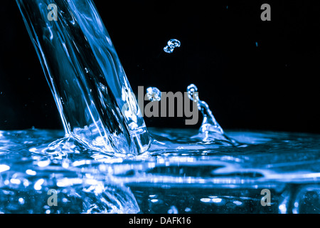 Eine schöne Form, erstellt von der flüssigen Bewegung von Wasser plantschen wie es gegossen wird. Stockfoto