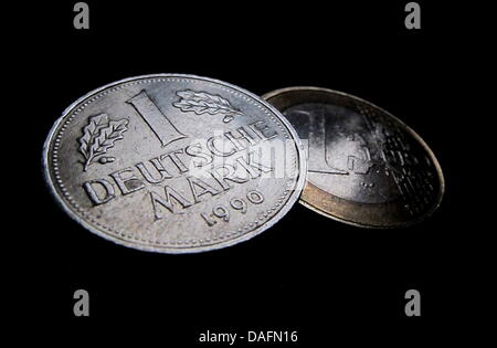 (Dpa Datei) - ein Datei-Bild datiert 17. Dezember 2010 zeigt ein Beispiel für eine Deutsche Mark Münze auf einem ein-Euro-Münze in Kaufbeuren, Deutschland. Auch zehn Jahre nach der Einweihung des Euro ist noch weithin als Leben teurer gemacht haben, aber seine Anhänger halten es weiterhin eine gute Idee sein. Foto: Karl-Josef Hildenbrand Stockfoto