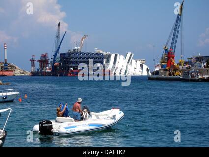 Giglio, Italien. 10. Juli 2013. Ein Boot fährt vorbei an den Bergungsarbeiten am Wrack des Kreuzfahrtschiffes "Costa Concordia" vor der Küste der Insel Giglio, Italien, 10. Juli 2013. Foto: MIRIAM SCHMIDT/Dpa/Alamy Live News Stockfoto