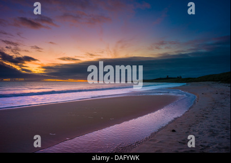 Vor Sonnenaufgang an der Northumberland Küste mit Dunstandburgh Castle in der Ferne Licht. Stockfoto