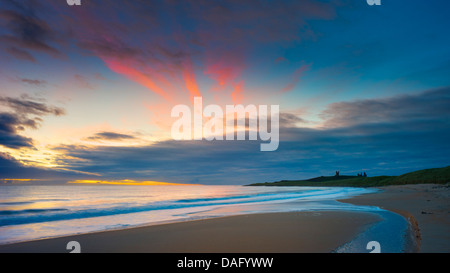 Vor Sonnenaufgang an der Northumberland Küste mit Dunstandburgh Castle in der Ferne Licht. Stockfoto