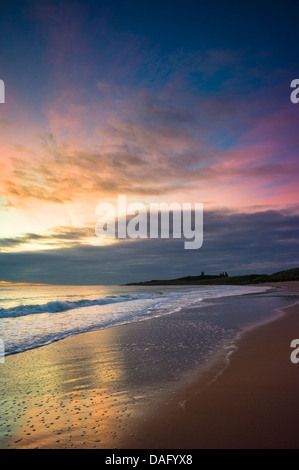 Vor Sonnenaufgang an der Northumberland Küste mit Dunstandburgh Castle in der Ferne Licht. Stockfoto