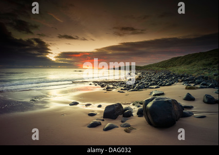 Vor Sonnenaufgang an der Northumberland Küste mit Dunstandburgh Castle in der Ferne Licht. Stockfoto