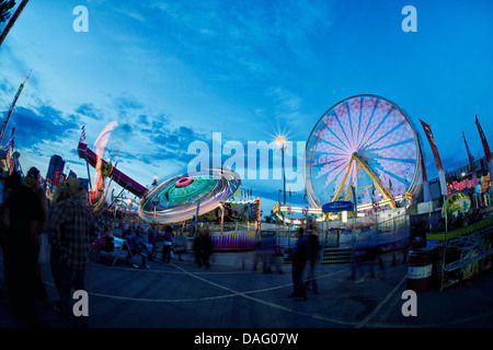 Calgary Stampede, Amusement Rides auf der Midway in der Abenddämmerung. Riesenrad und Fahrten mit ihren Lichtern auf dreht und dunklen Himmel Stockfoto