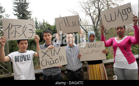 Minderjährige Flüchtlinge Thahn, Tuan und Vinh aus Vietnam sowie Shukri aus Somalia und Samina von Äthiopien Pose mit Zeichen in Nürnberg, 18. März 2011. Die Zeichen zeigen "Hallo" in verschiedenen Sprachen. Bayerische Ministerin für Soziales, Christine Haderthauer (m) einen Unterstand für minderjährige Flüchtlinge in Nürnberg besucht. Foto: DANIEL KARMANN Stockfoto