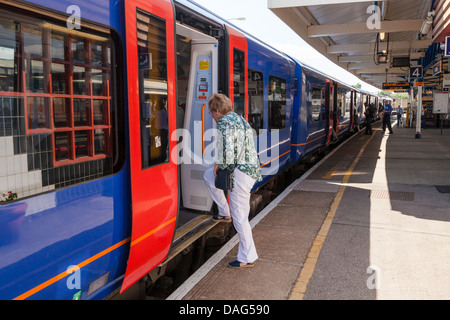 Eine Frau einsteigen in einen Zug allein am Bahnhof Vauxhall, London, England, UK Stockfoto