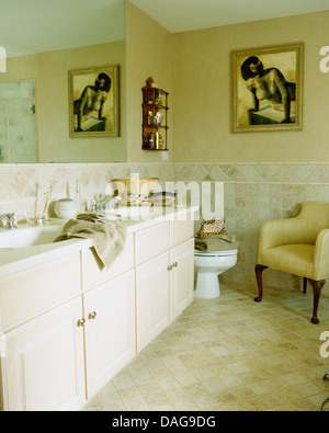 Doppel-Waschbecken legen Sie im Schrank fest im Badezimmer mit figurativen Gemälde an der Wand über dem WC und gelbe Sessel Stockfoto