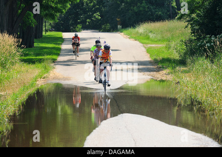 Radfahrer, die teilweise überfluteten Landstraße unterwegs. Stockfoto