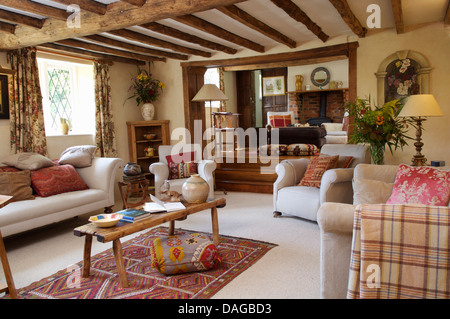 Weiße Sofas und Sessel mit rustikaler Couchtisch aus Holz in Holzbalken Ferienhaus Wohnzimmer mit weißen Teppich Kelim Teppich Stockfoto