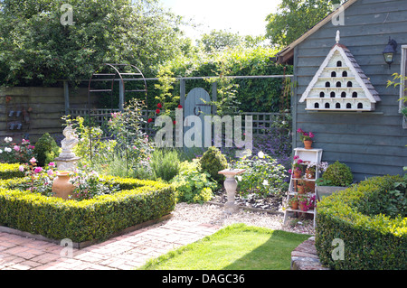 Ziegel-Pfade und niedrigen Box Absicherung um Parterre Betten im Bauerngarten mit alten weißen gemalten Taubenschlag an Wand gemalte Hütte Stockfoto