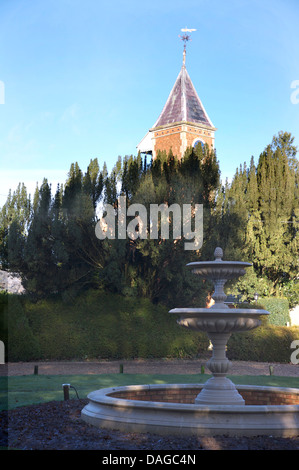 Stein-Brunnen in kreisförmigen Pool im großen Garten mit hohen Turm über Bäume Stockfoto