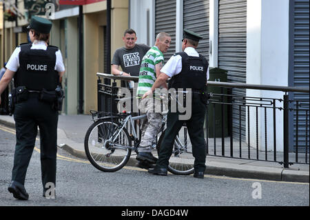 Londonderry, Nordirland, Vereinigtes Königreich. 12. Juli 2013. PSNI Offiziere stoppen ein Nationalist in der Nähe, wo lokale Mitglieder einer der Oranier-Orden von einer Parade zum 325. Jahrestag der Schlacht am Boyne zurückzugeben. Stockfoto