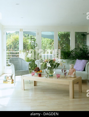 Holzboden und blass blauen Sofa und Lloyd Loom Stuhl in Verlängerung der hellen und luftigen Wohnzimmer mit großen Fenstern Stockfoto