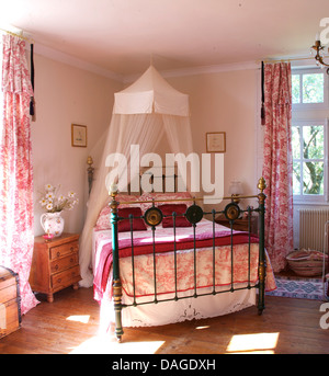 Weißen Voile Moskitonetz über dem Messingbett mit Toile De Jouy Cover auf der französischen Land Schlafzimmer mit Toile De Jouy Gardinen Stockfoto