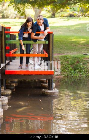 Süße Teenager-paar Fütterung Fische am Teich Stockfoto